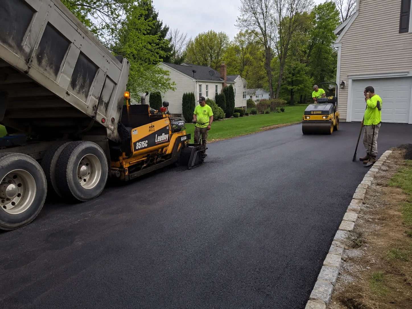 Asphalt paving crew using a LeeeBoy paver machine on a residential driveway in New York