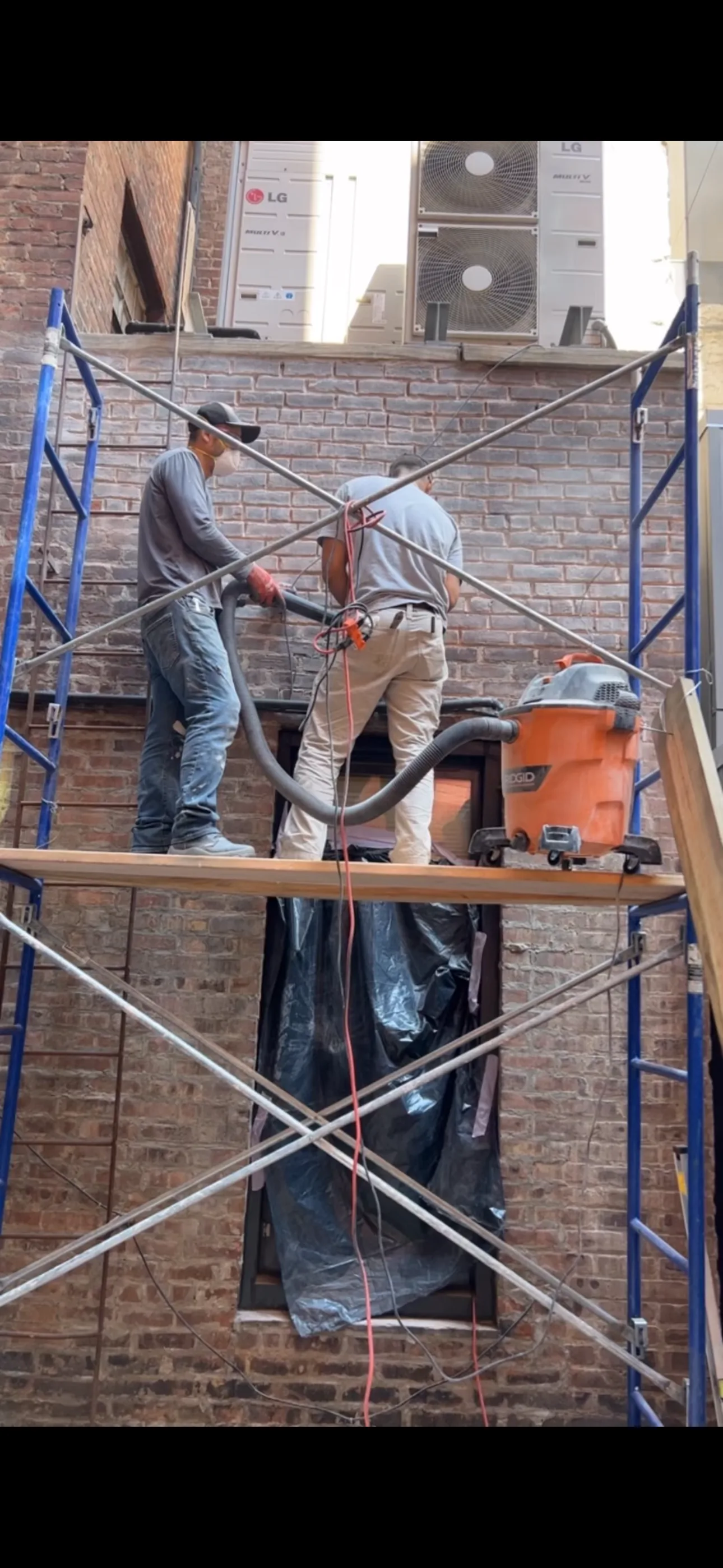 Workers doing brick pointing on scaffolding in New York City
