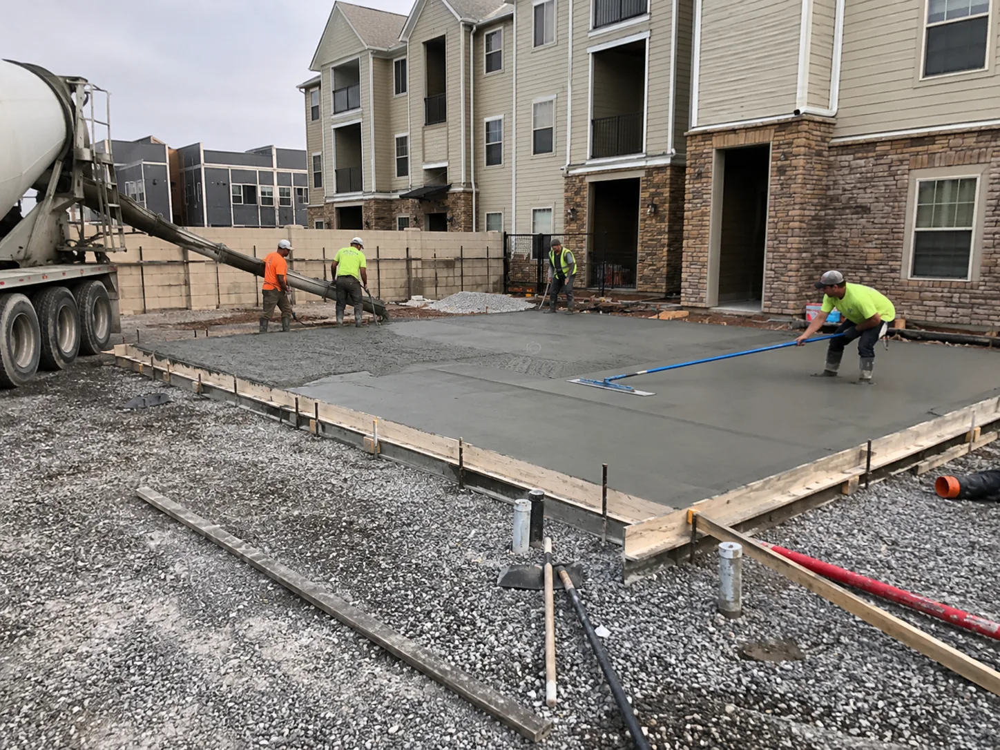 Commercial concrete pour with mixer truck and crew at a multi-unit apartment complex in New York