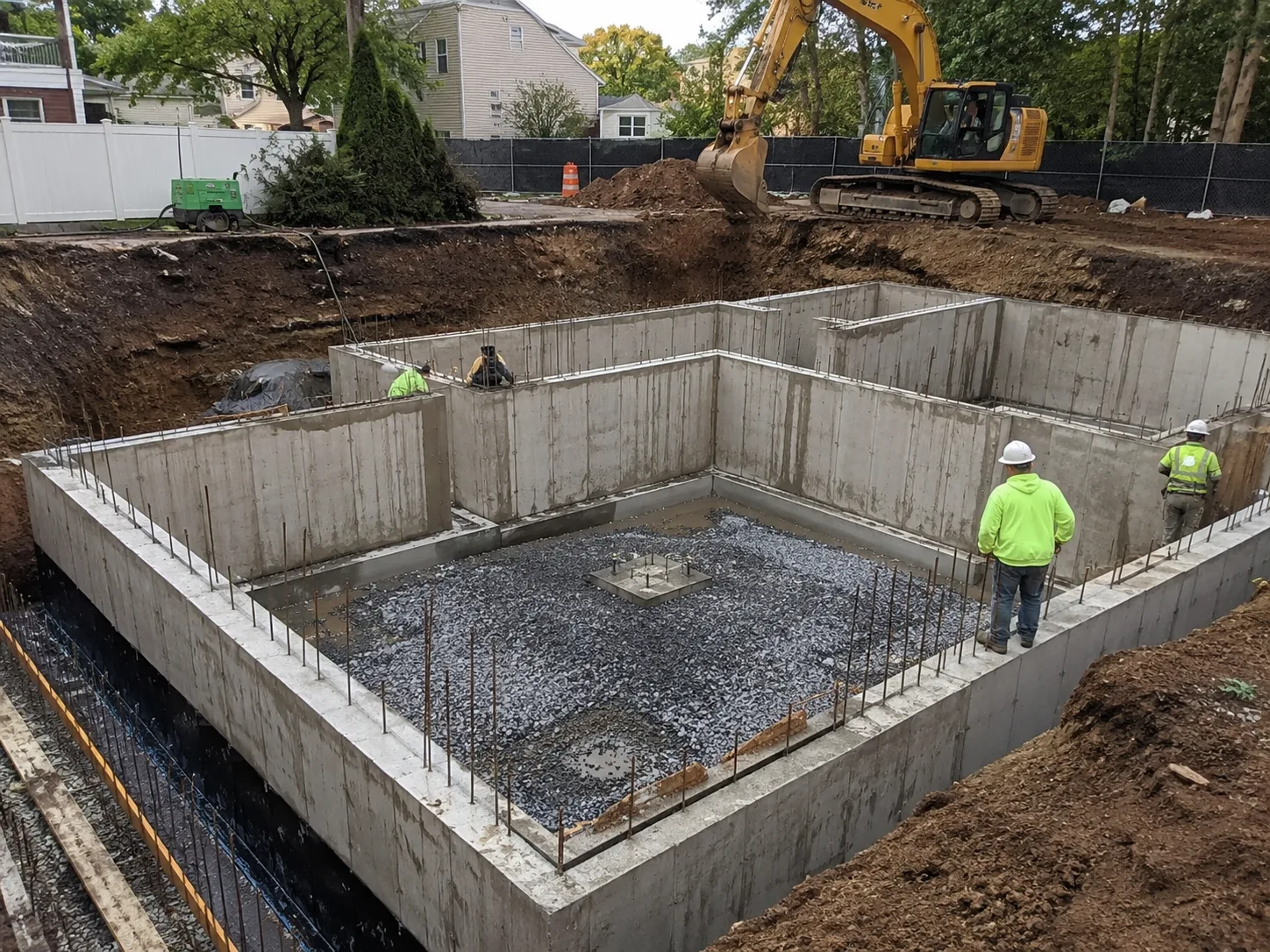 Residential concrete foundation with excavator on job site in New York