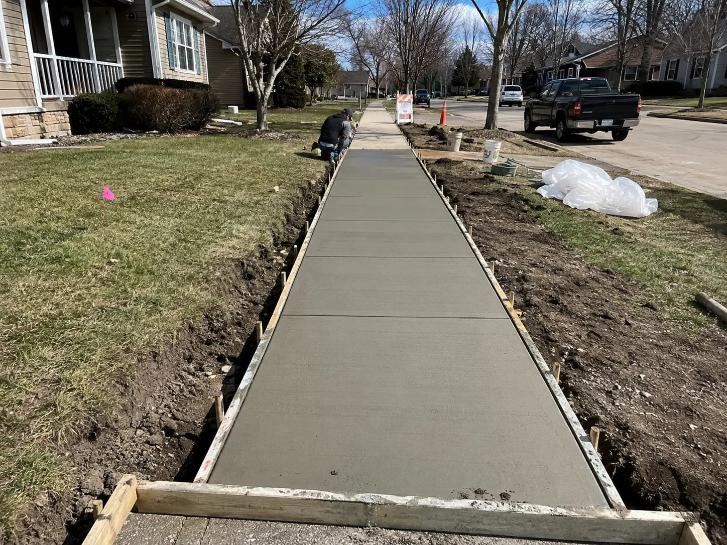 Crew installing a new concrete sidewalk with control joints in a New York suburb